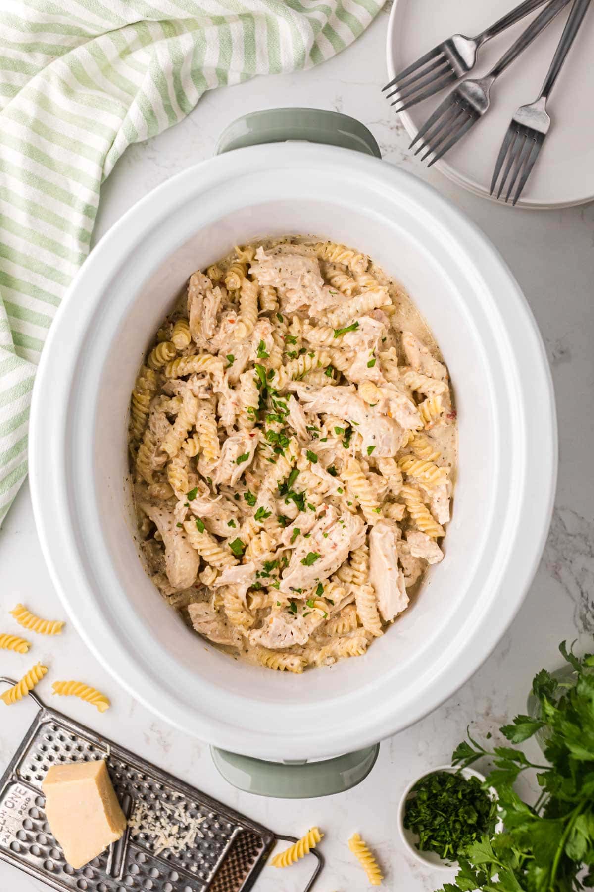 A crock pot filled with creamy parmesan garlic chicken pasta.