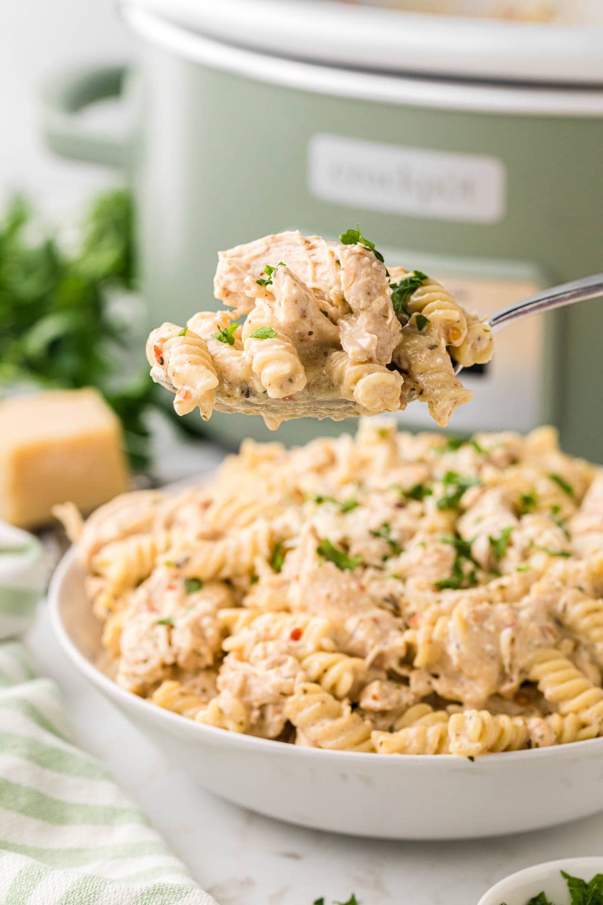 A spoon scooping up a serving of garlic parmesan chicken pasta.