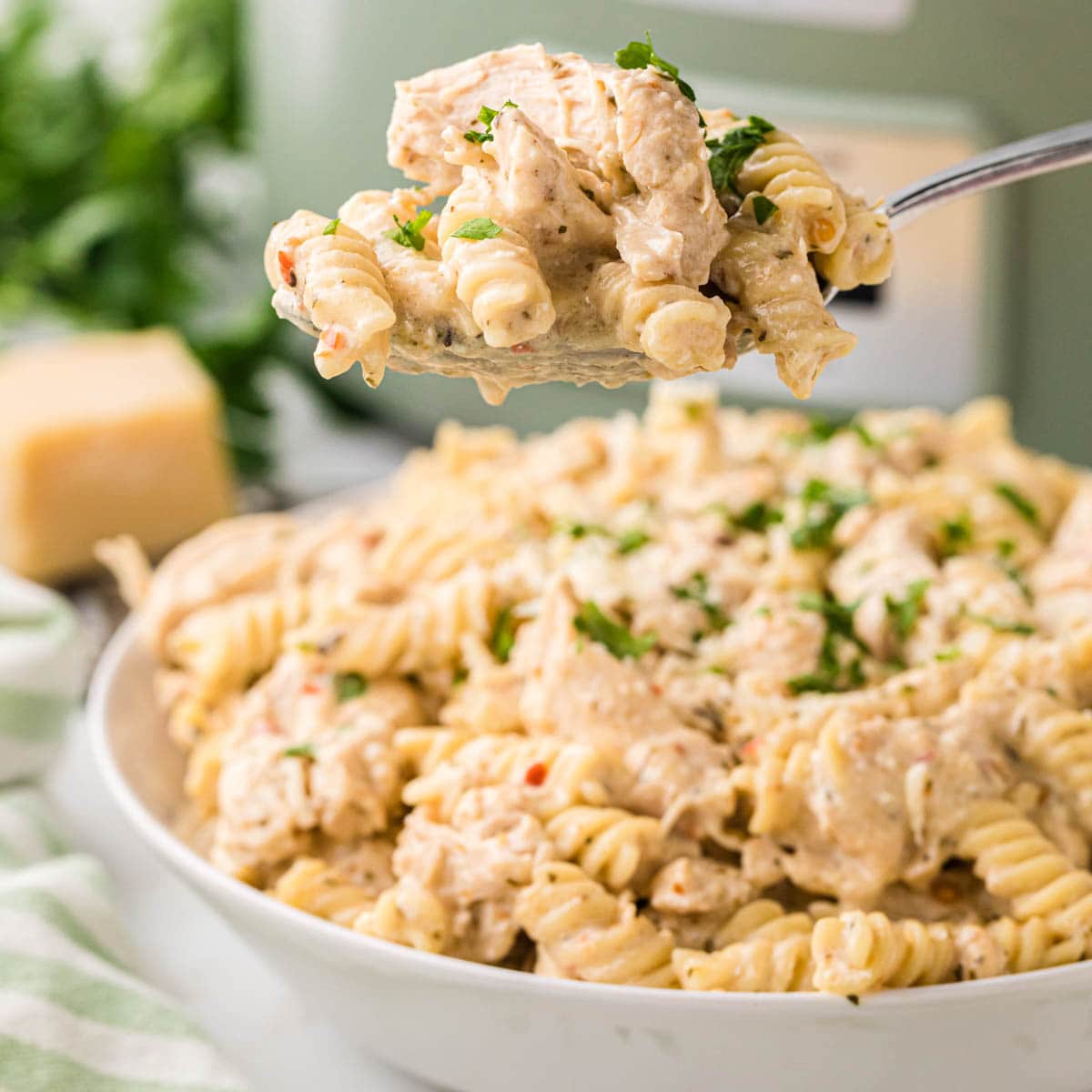 A spoon scooping up a serving of garlic parmesan chicken pasta.