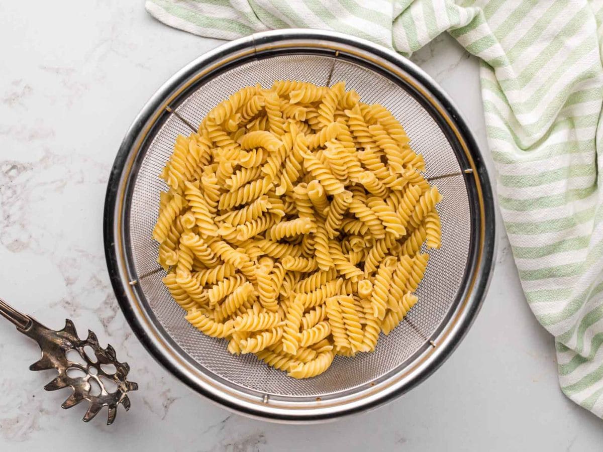 Cooked rotini pasta straining in a colander.