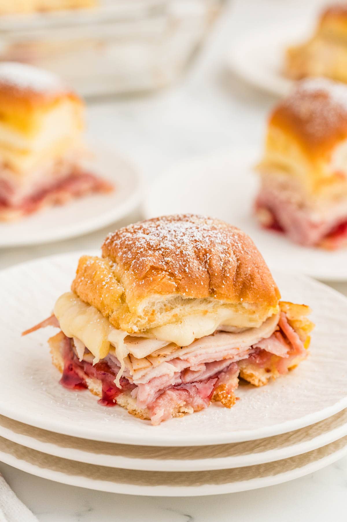 Monte cristo slider served on a stack of plates with more sliders in the background.