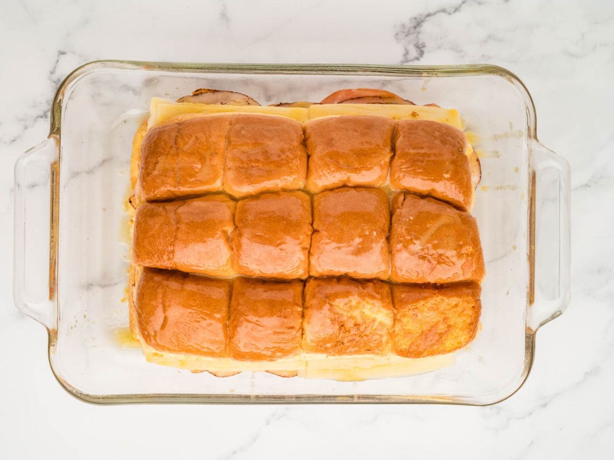 Monte cristo sliders assembled in a baking dish with a dijon egg glaze brushed on top.