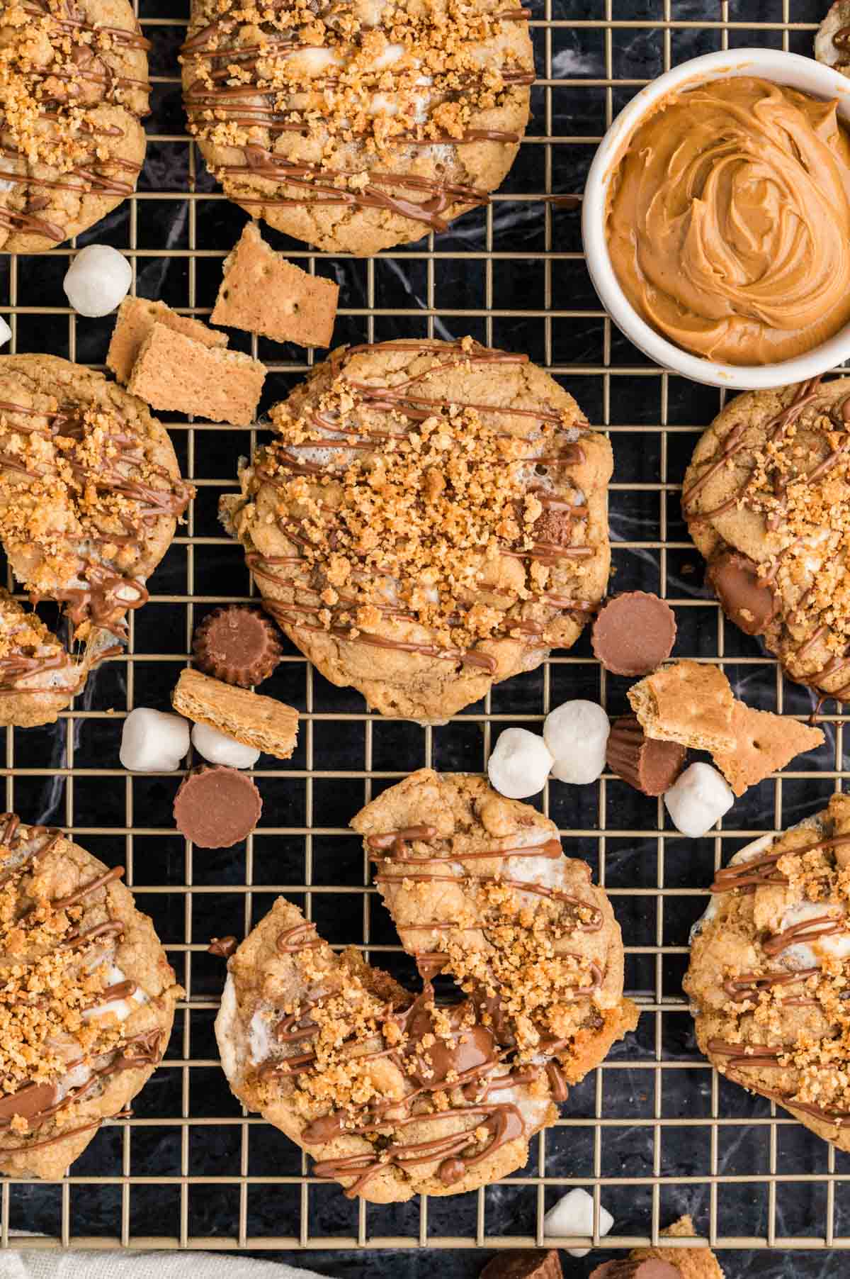 S'mores cookies on a cooling rack with graham cracker pieces and mini marshmallows.