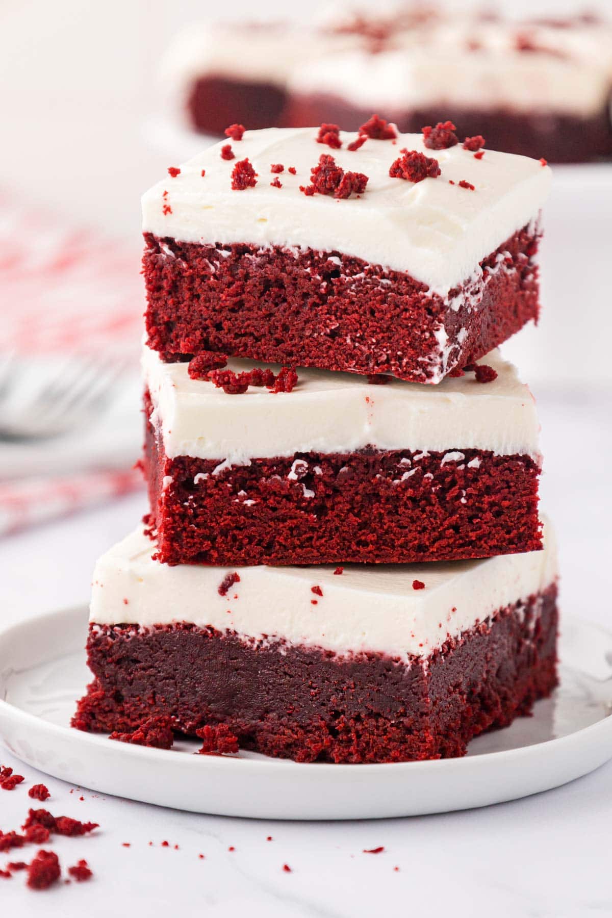 Three red velvet brownies stacked on a white plate.