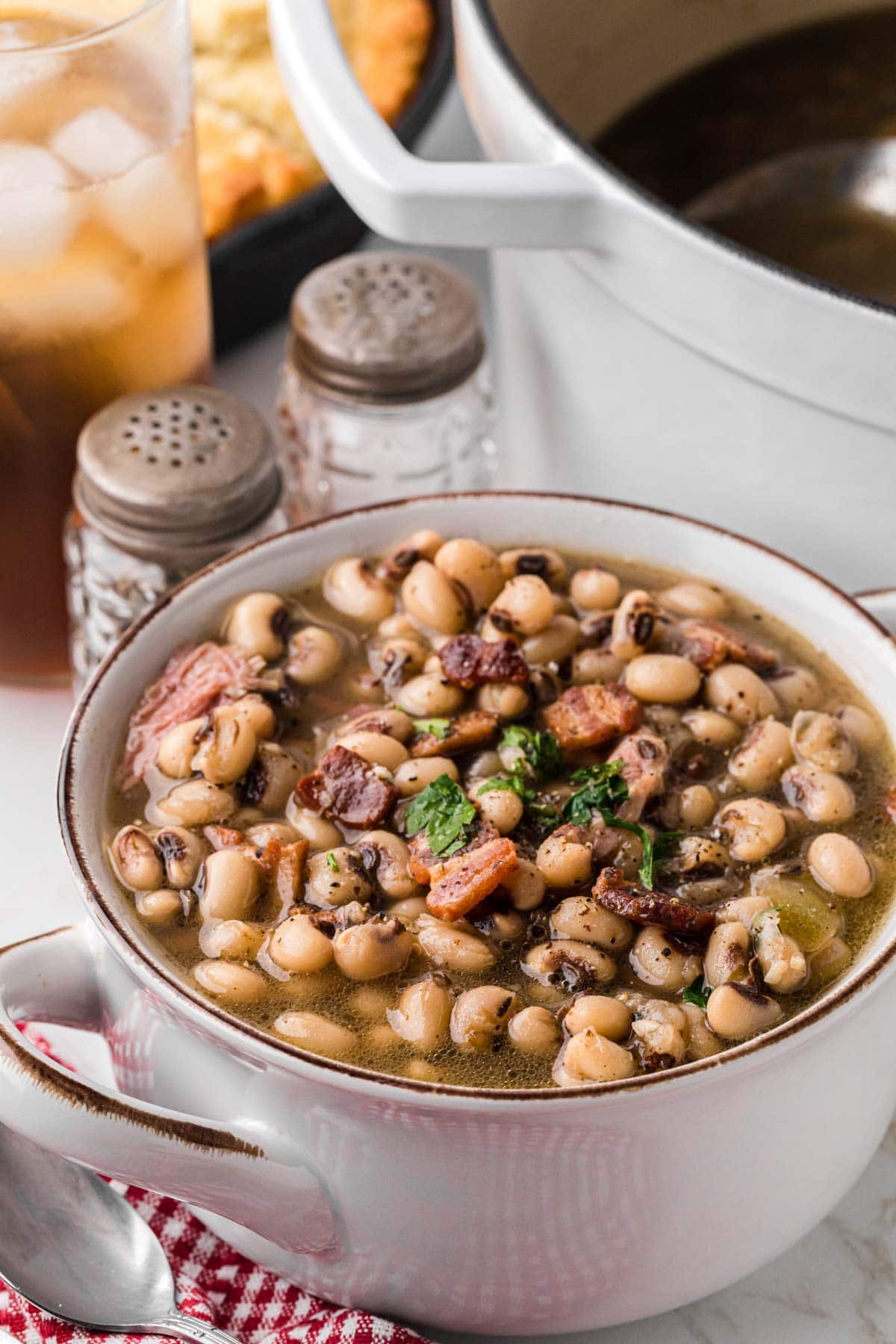 A bowl of Black Eyed Peas with a salt and pepper shaker in the background.