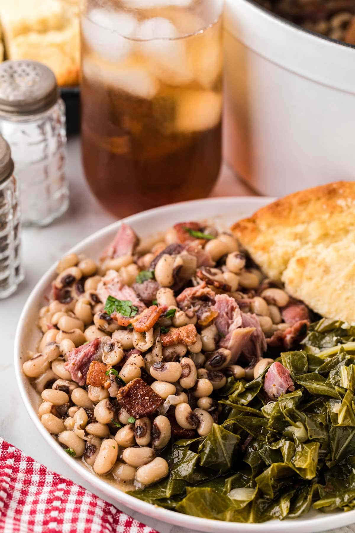 A plate of Black Eyed Peas served with collard greens and cornbread.