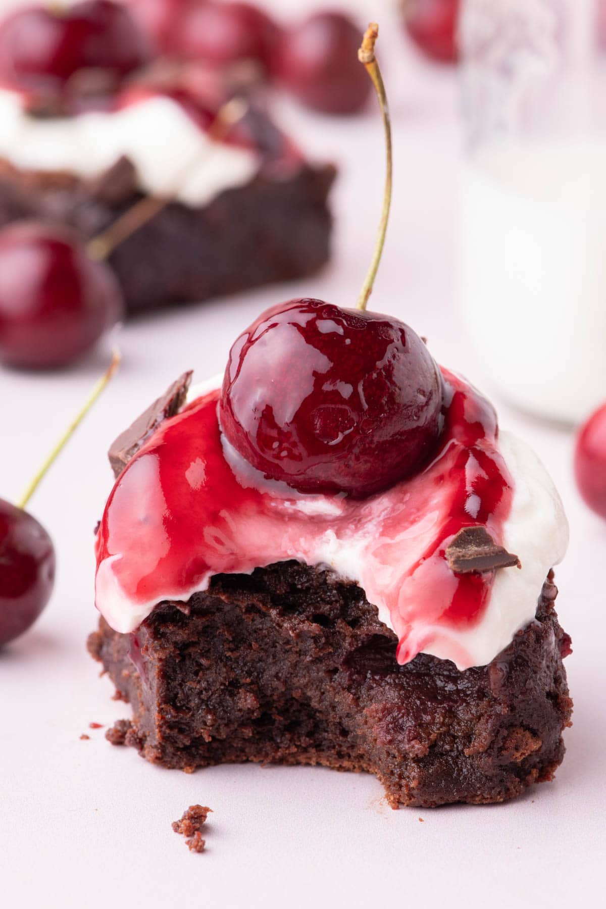 Black forest brownie with a small bite taken out of it and a fresh cherry on top.