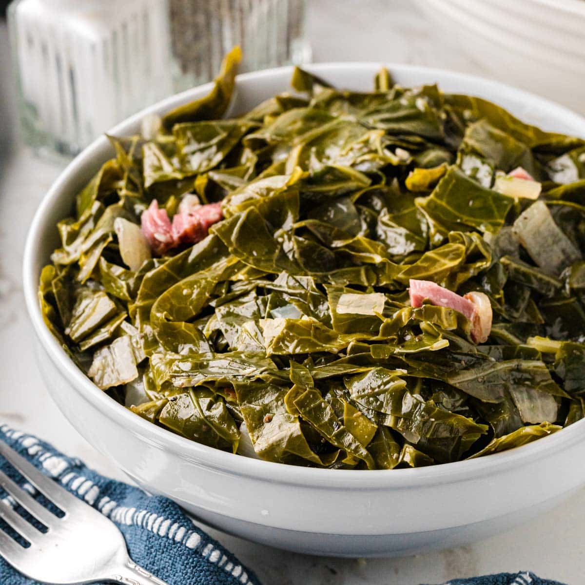 A bowl of southern collard greens in a white bowl.