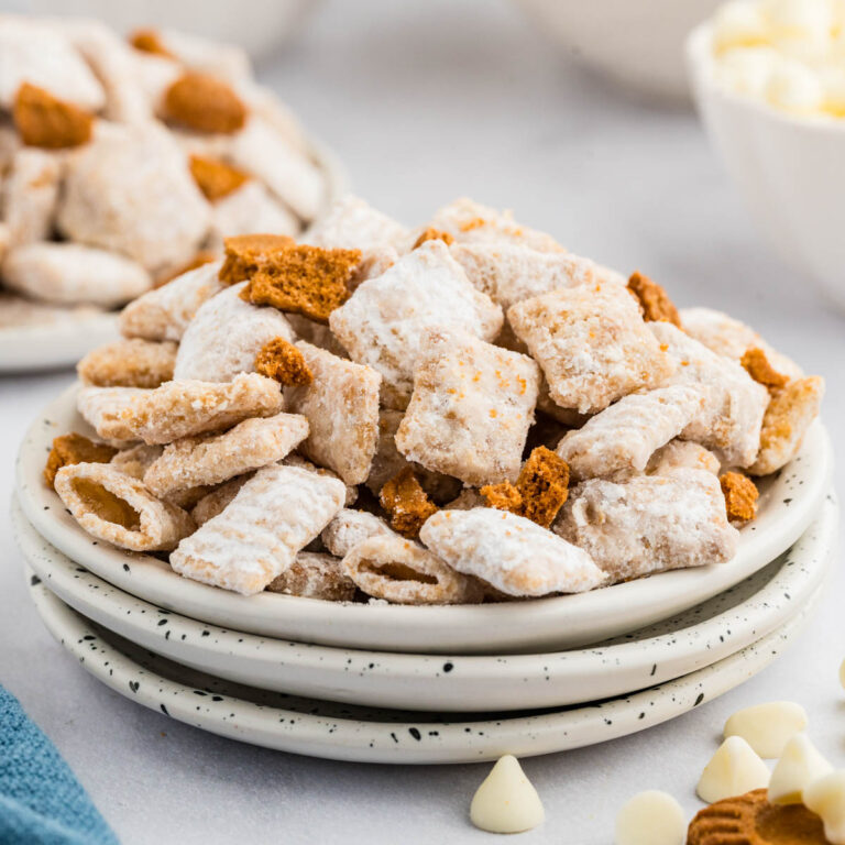 Side view of muddy buddies served on a stack of plates.