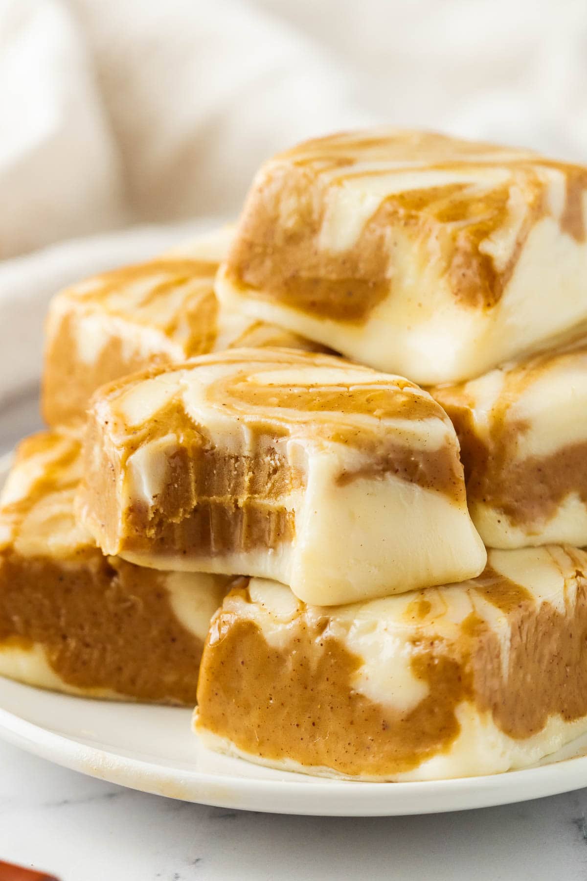 Squares of gingerbread swirl fudge stacked on top of each other on a plate.