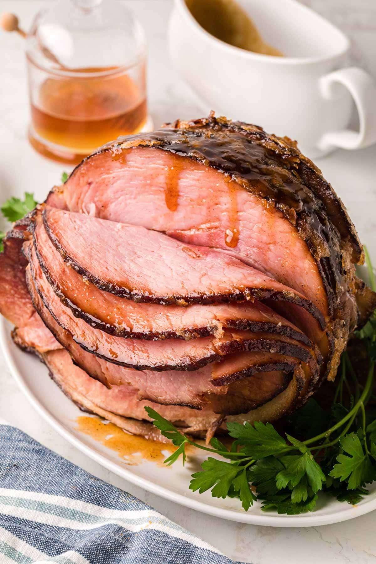 A slice spiral ham on a white platter garnished with parsley.