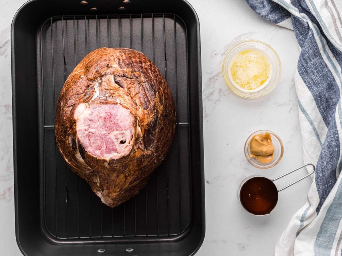 A spiral ham laid on the roasting rack in a roasting pan.