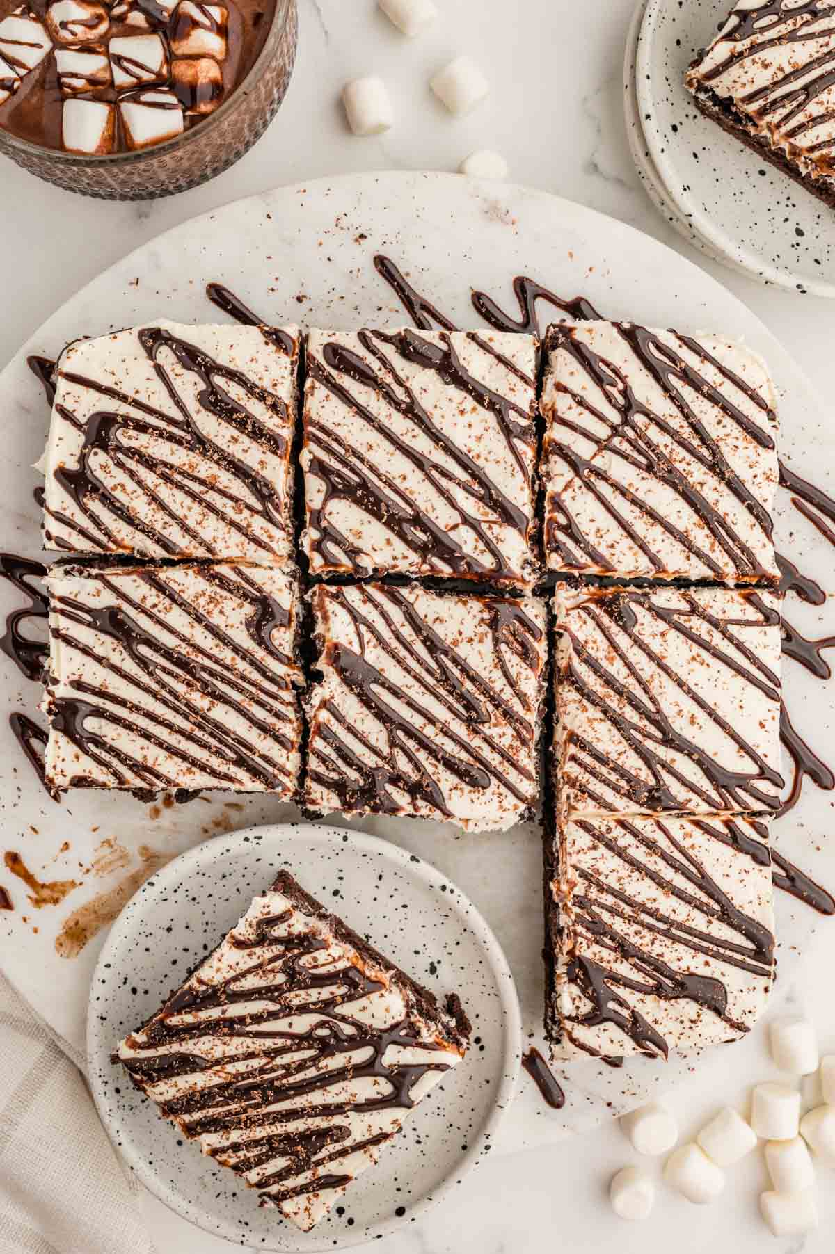 Hot chocolate brownies cut into squares with drizzled chocolate on top and one brownie on a plate.