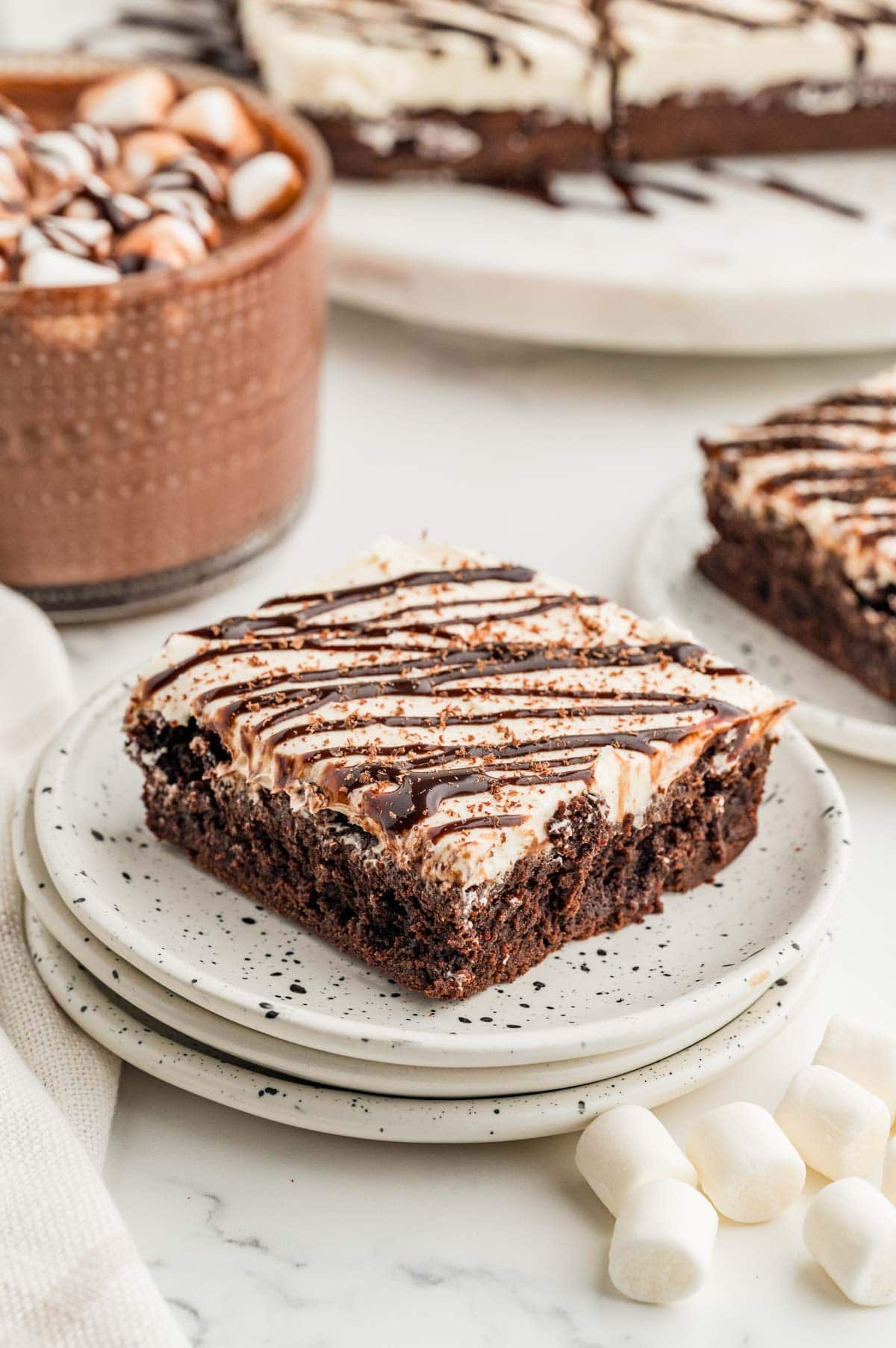 Hot chocolate brownie on a stack of speckled white plates.