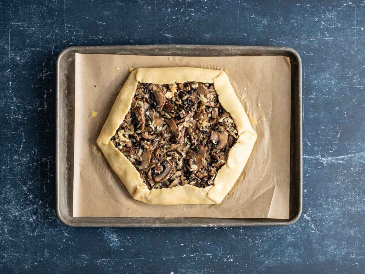 Assembled mushroom galette on a baking sheet lined with parchment paper before being baked.