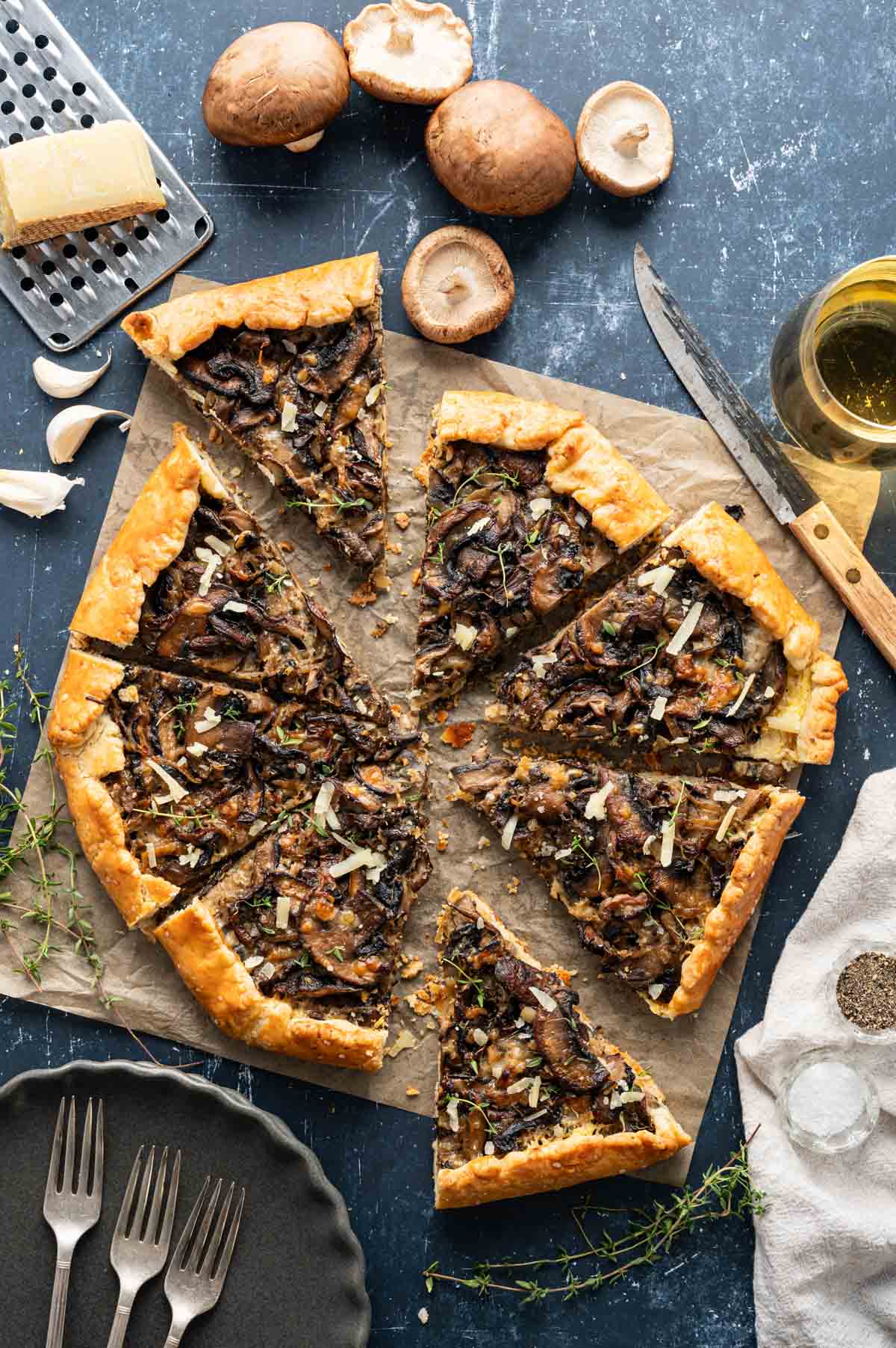 Slices of mushroom galette on a parchment paper with thyme garnishing them on top.