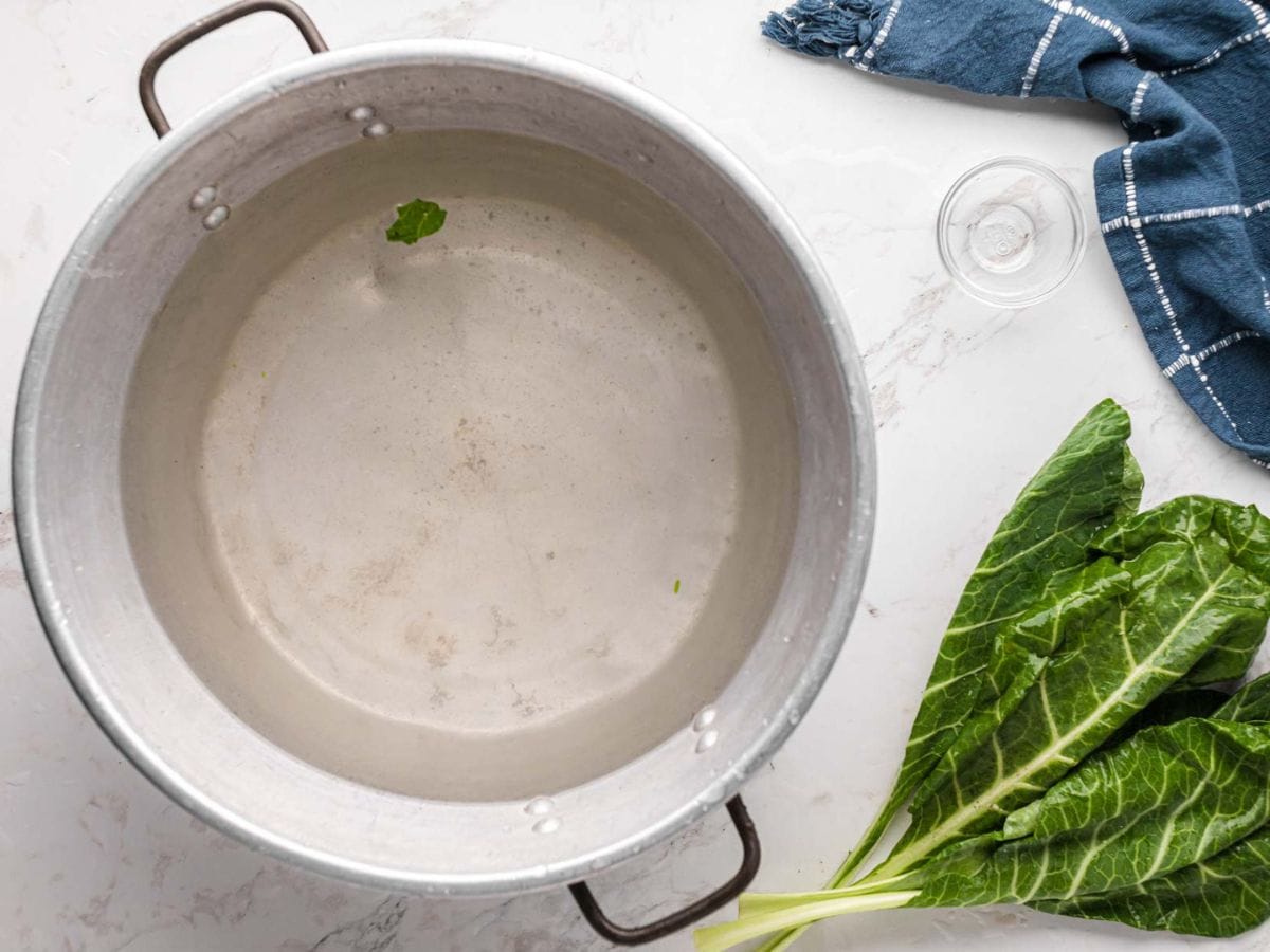 A large pot of water with sand from collard greens and bottom.