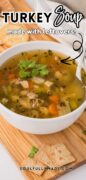 Easy turkey soup recipe is featured in a white bowl and served with crackers.