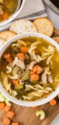 Easy turkey soup recipe is featured in a white bowl and served with noodles.