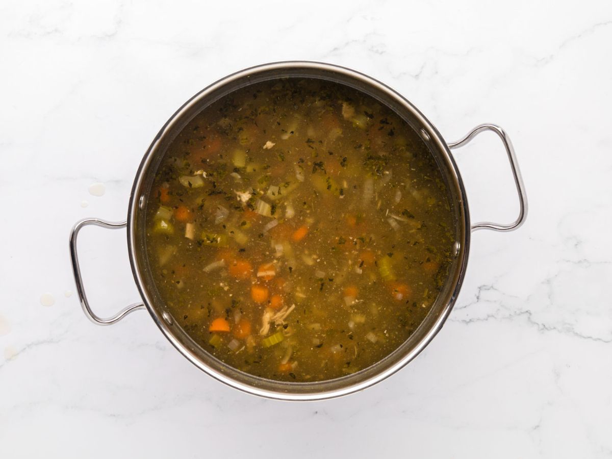 A soup pot filled with cooked turkey soup.