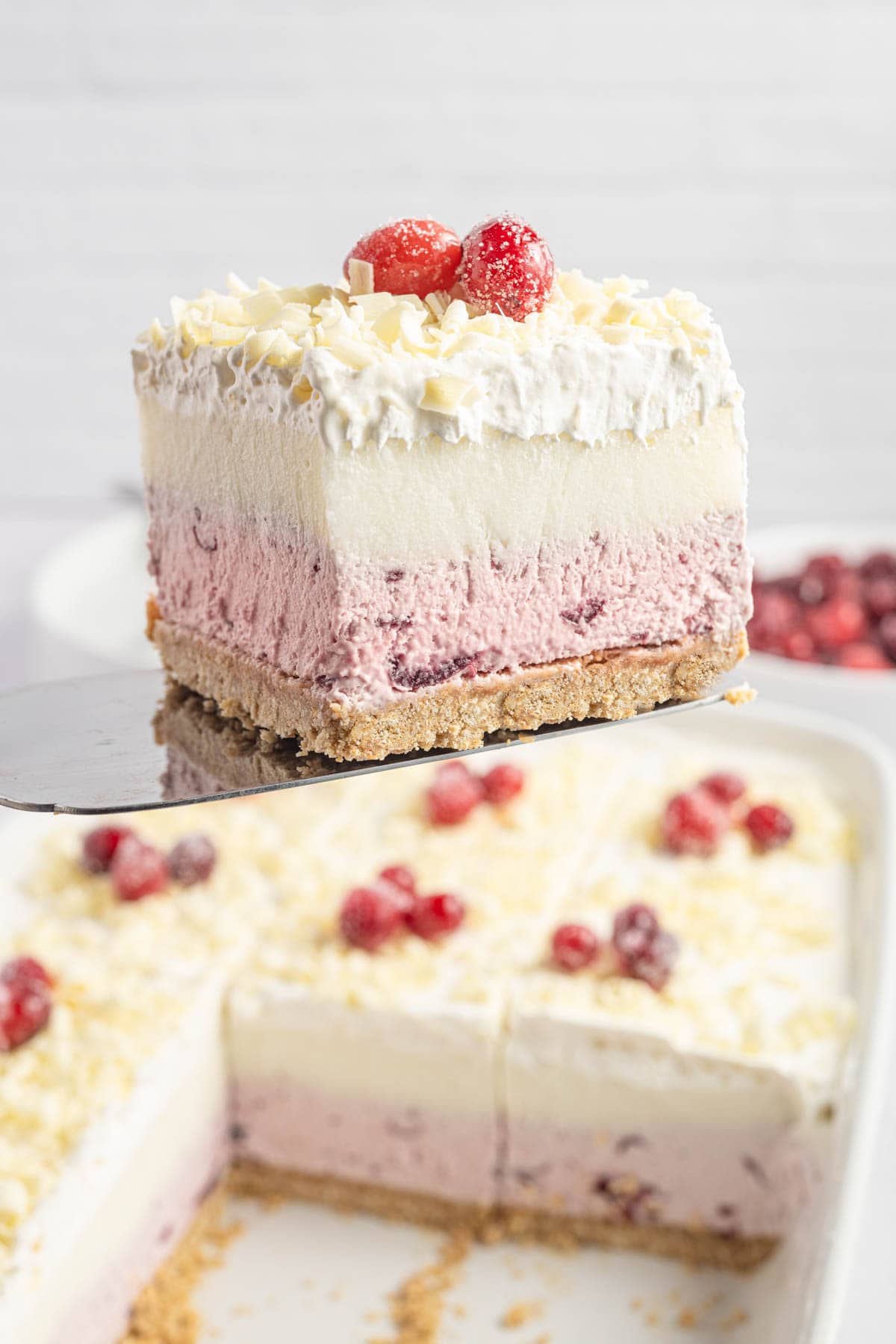 Slice of cranberry dessert on a spatula with the remaining dessert below it.