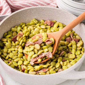 A wooden spoon scooping out serving of southern style green lima beans.