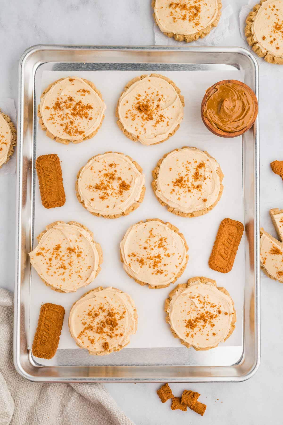 Overhead shot of cookie butter cookies on a sheet pan with frosting on top.