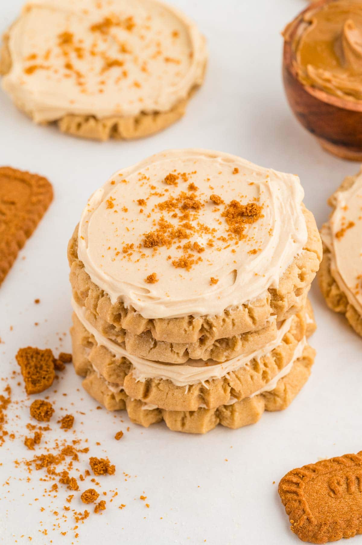 Stack of biscoff cookies with frosting and cookie crumbs sprinkled on top.