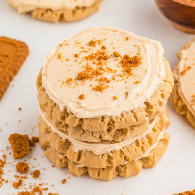 Stack of frosted cookie butter cookies with a sprinkle of biscoff cookie crumbs on top.