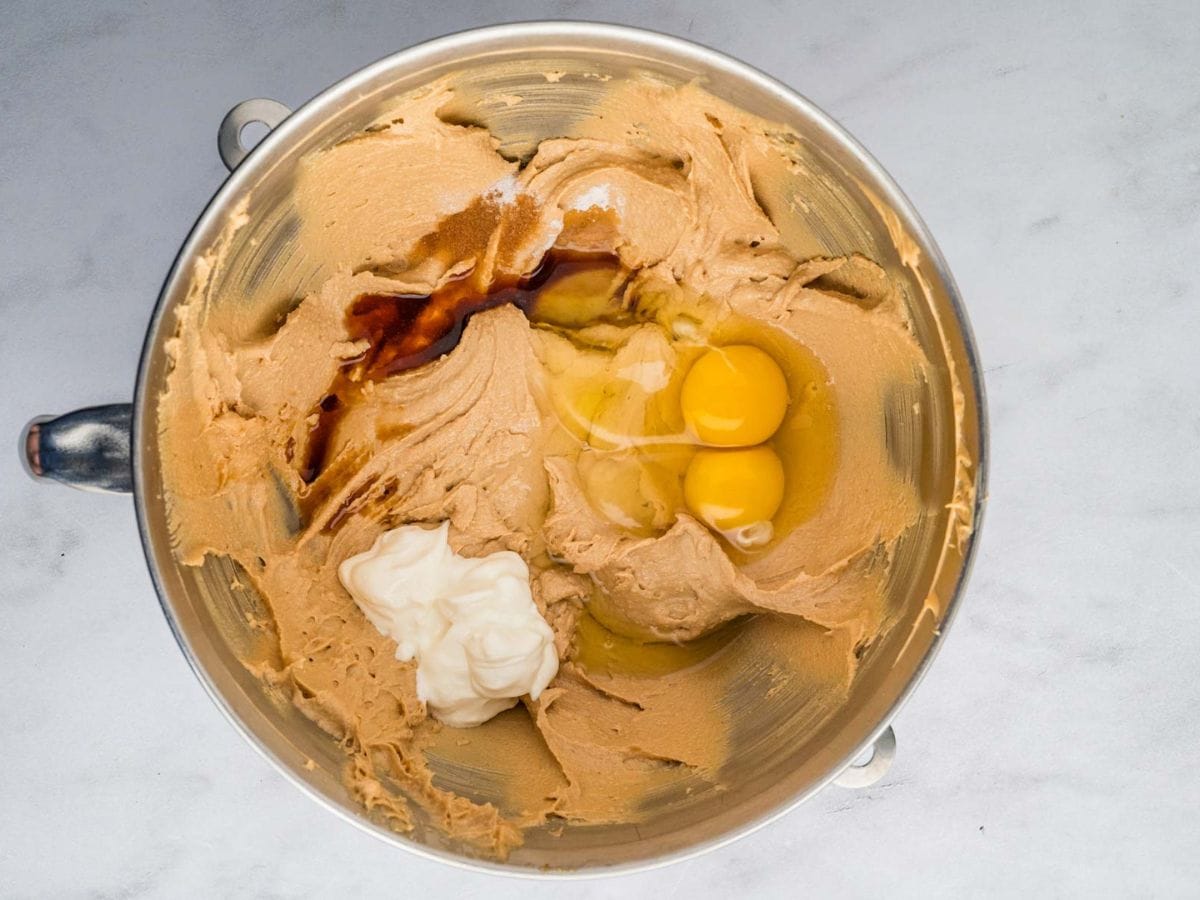 Adding the eggs, sour cream, and vanilla to the cookie dough.