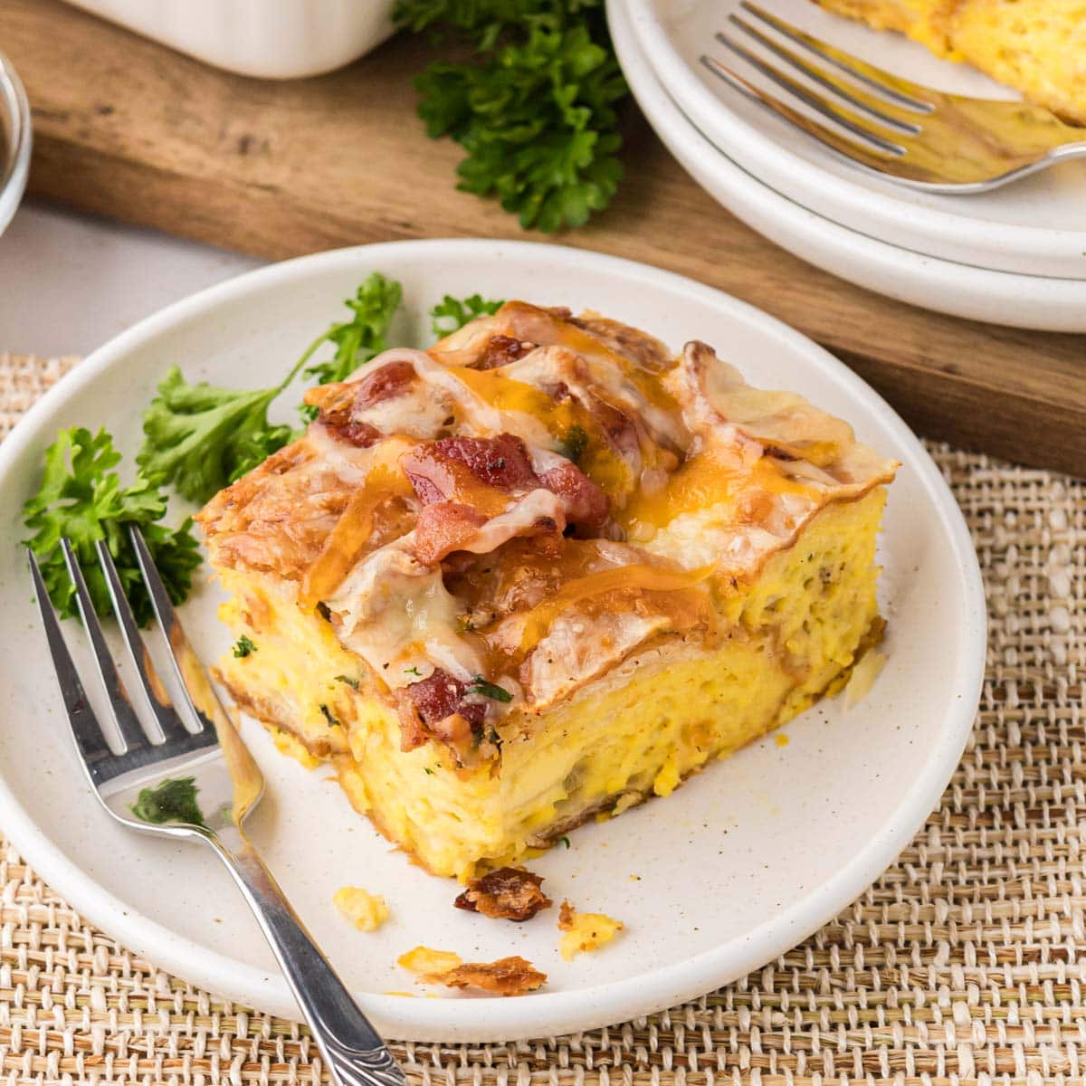 A white speckled plate with a slice of croissant casserole with bacon and Gruyere cheese.