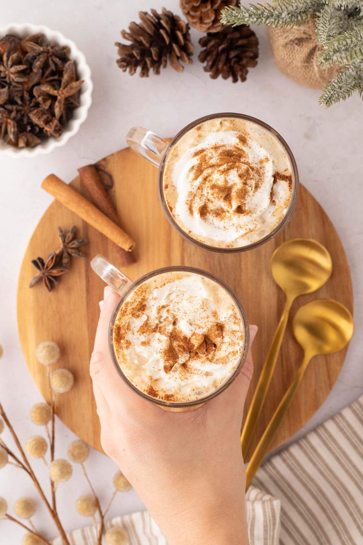 A hand removing a latte from a round wooden board.