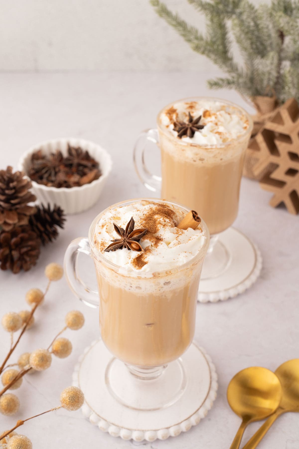 Two eggnog latte set on a white wooden coaster.