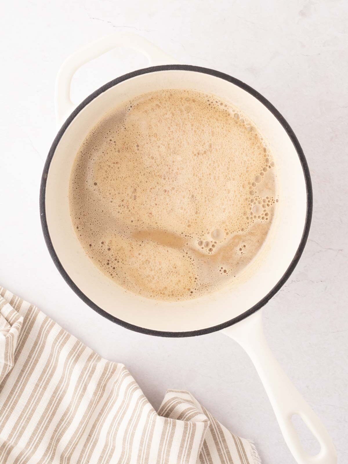 Eggnog latte mixture and a white sauce pan.