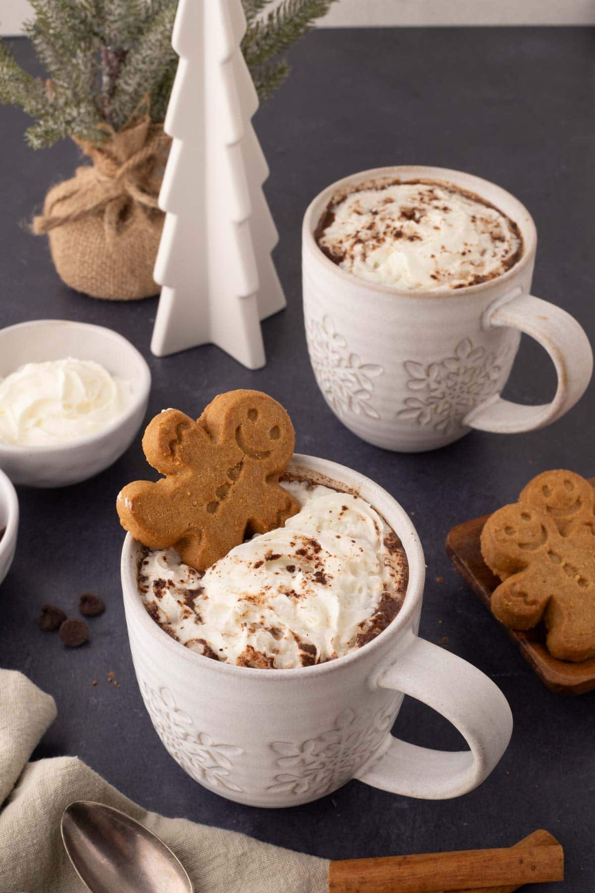 two white mugs with gingerbread hot cocoa.