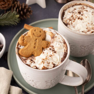 Two white mugs with gingerbread hot cocoa on a green serving plate.