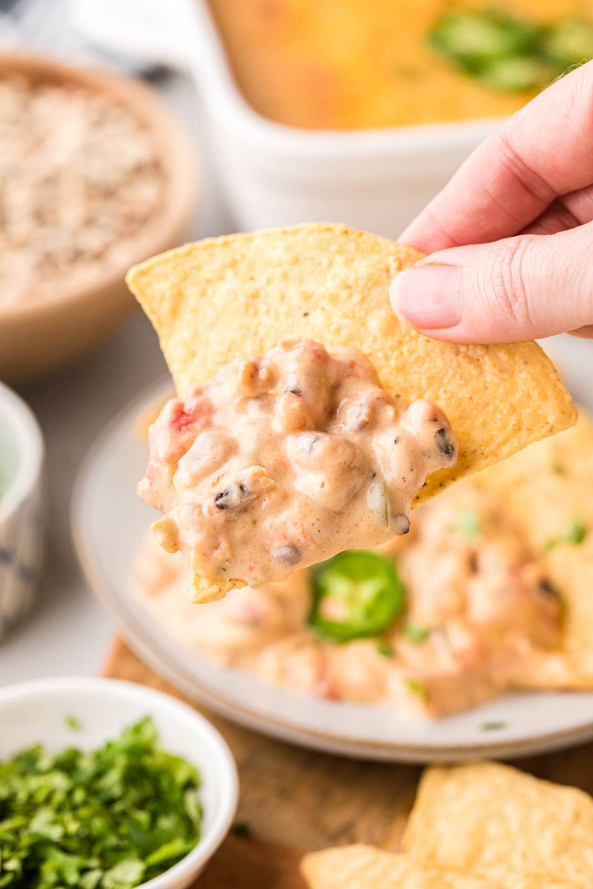 A hand picking up a scoop of black eye pea dip.