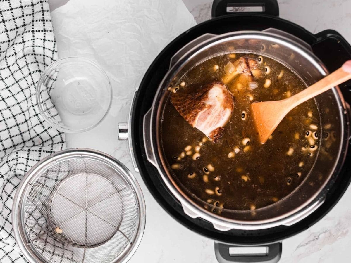 Stirring in Black Eyed Peas and ham into the broth before cooking.