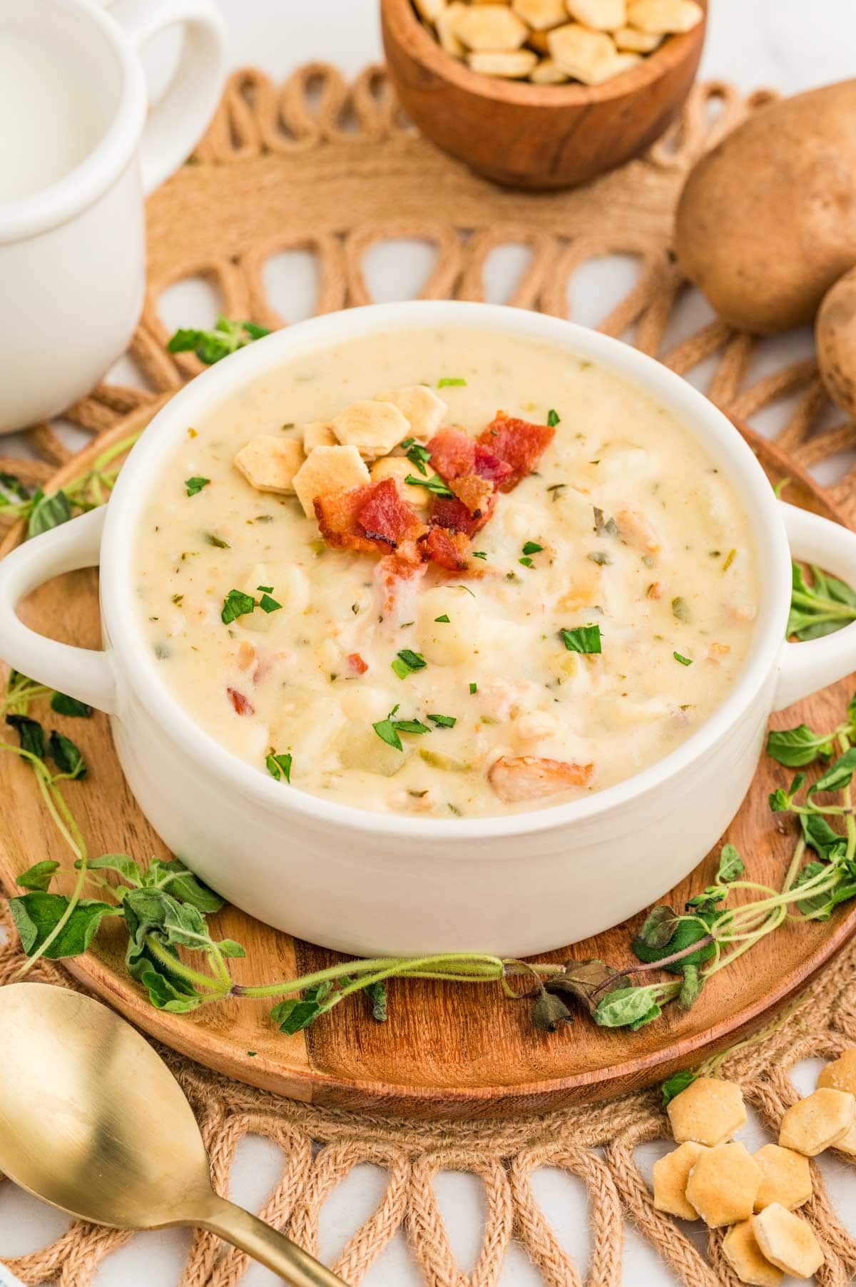 Clam chowder served in a soup bowl and garnished with oyster crackers and bacon.