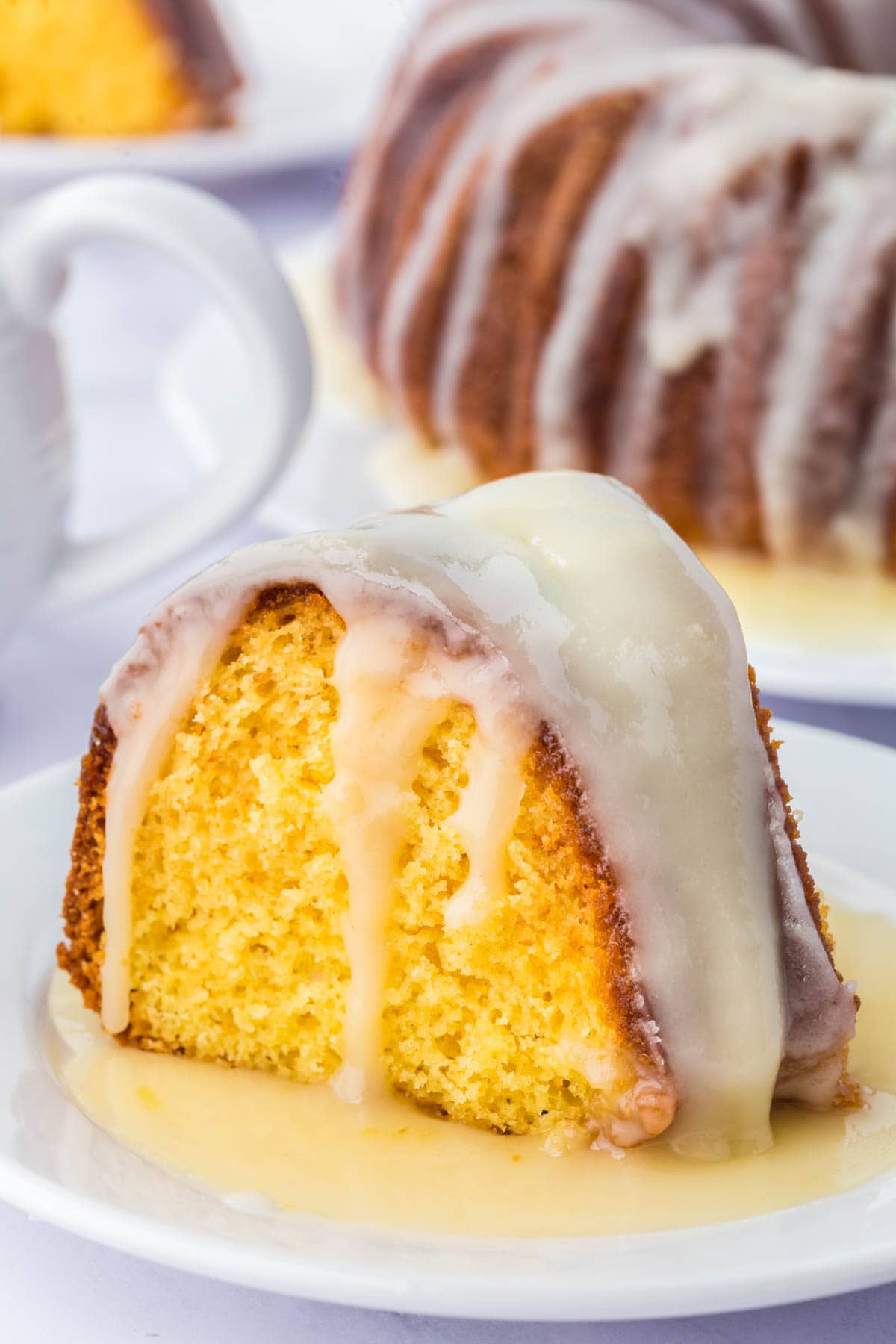 Slice of rum cake on a white plate with extra glaze poured over the top.