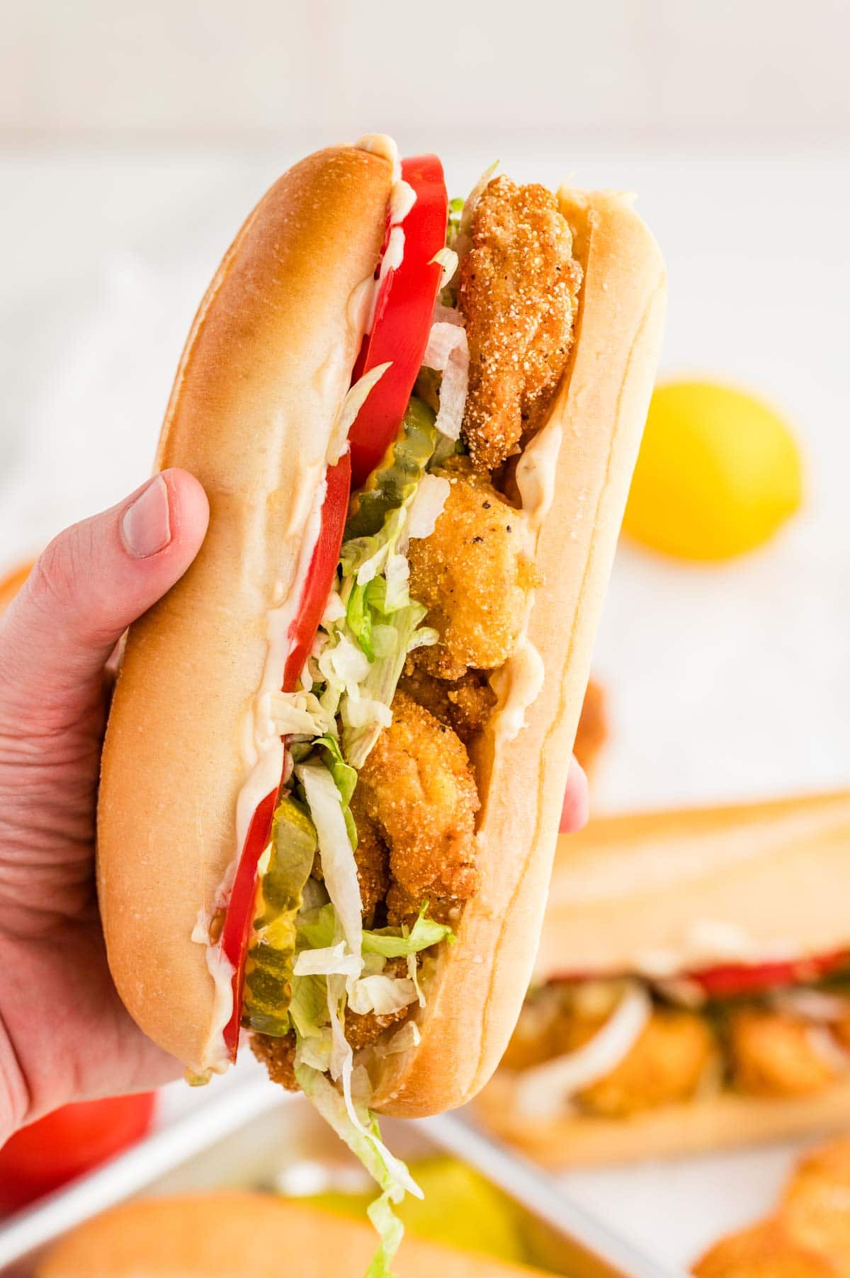 Hand holding a shrimp po boy sandwich to the camera.