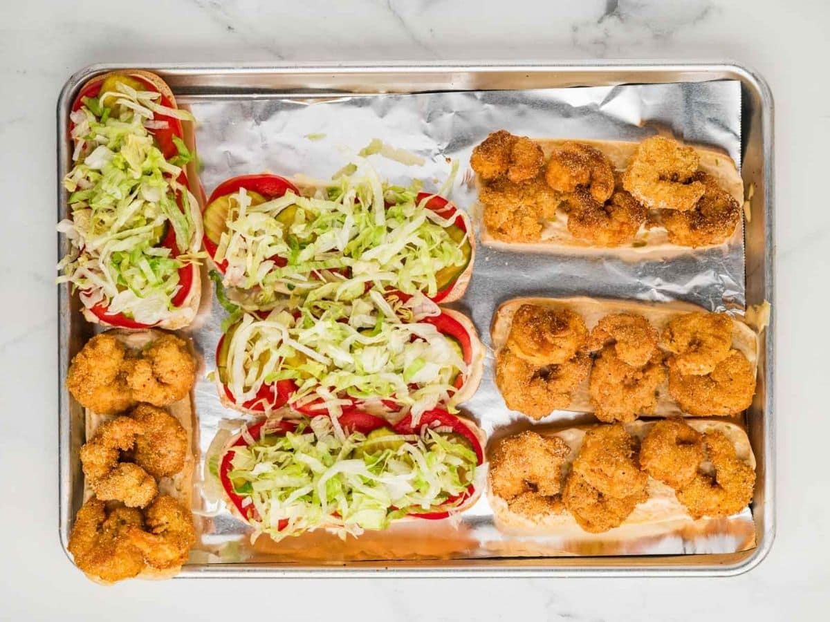 Assembling the shrimp po boy sandwiches on a sheet pan.