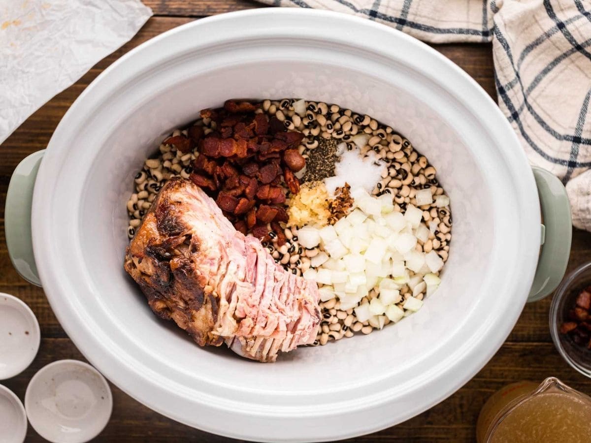 Bacon, ham, diced onion, garlic, and seasonings, added to the peas in the slow cooker.