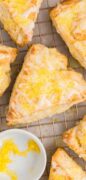 Lemon Cream Scones are on a wire rack with a bowl of yellow sanding sugar.