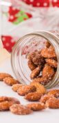 Honey Roasted Almonds are spilling out from a jar and there mis a strawberry tea towel in the background.