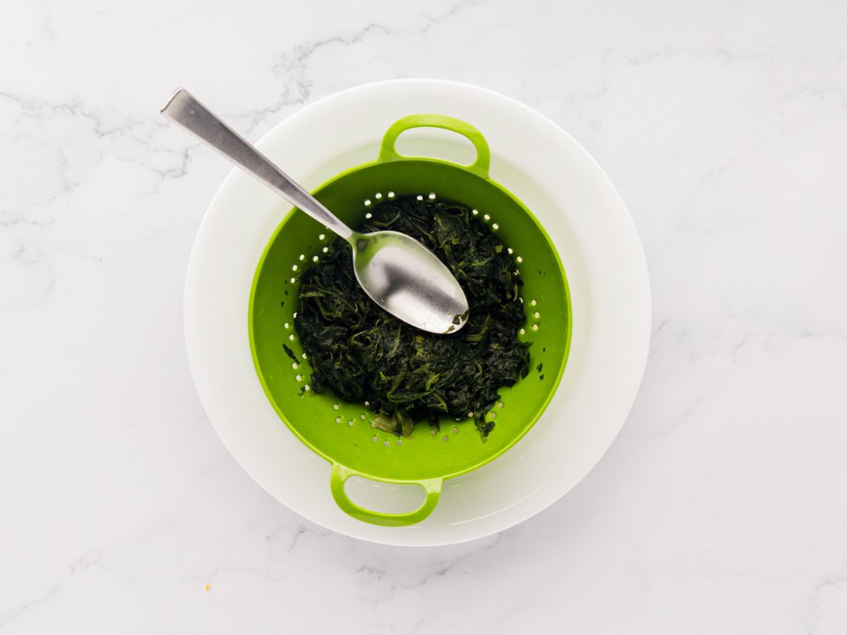 A colander with cooked spinach.