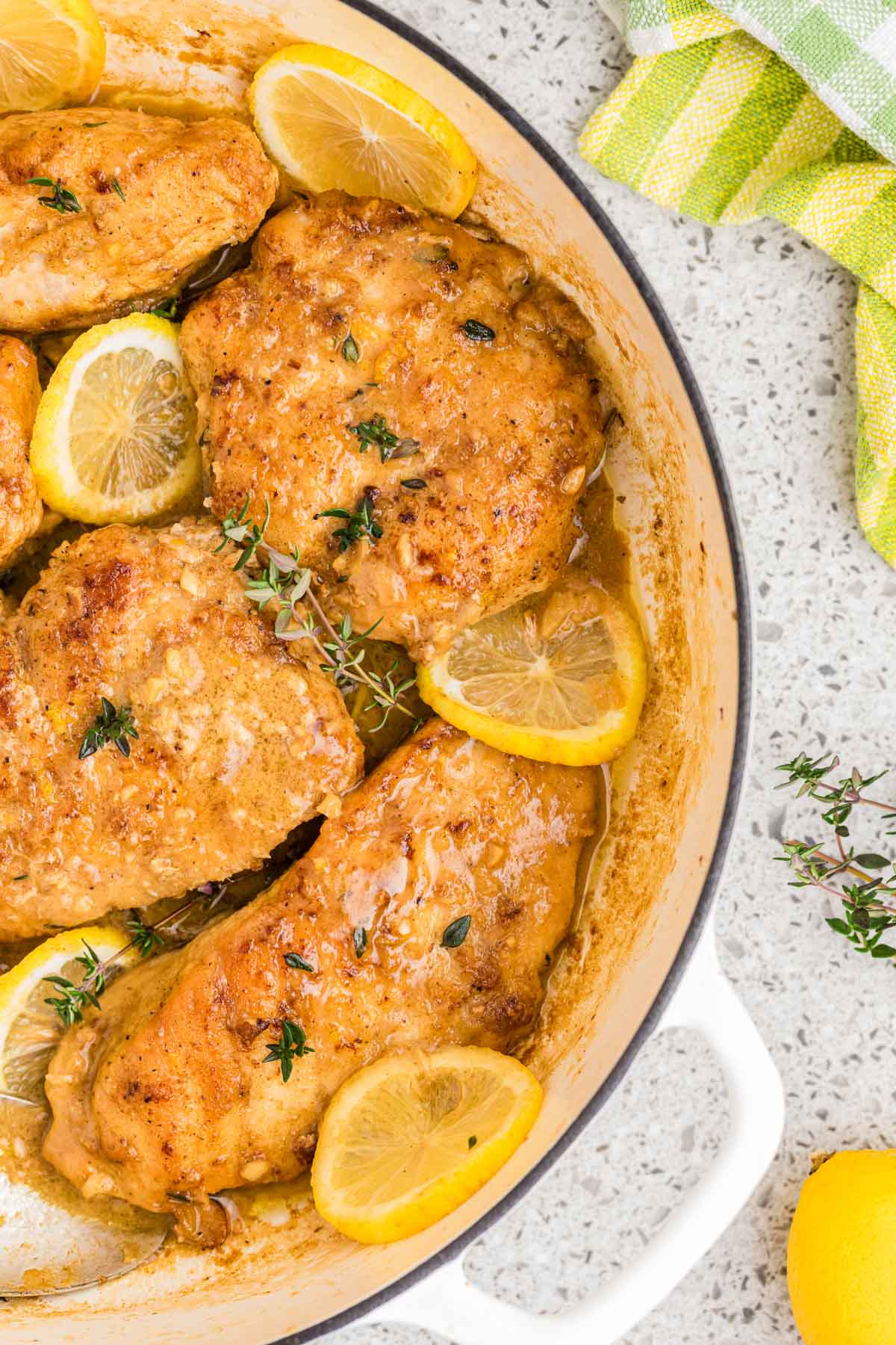 Overhead shot of lemon butter chicken in a pan with fresh lemon slices throughout.