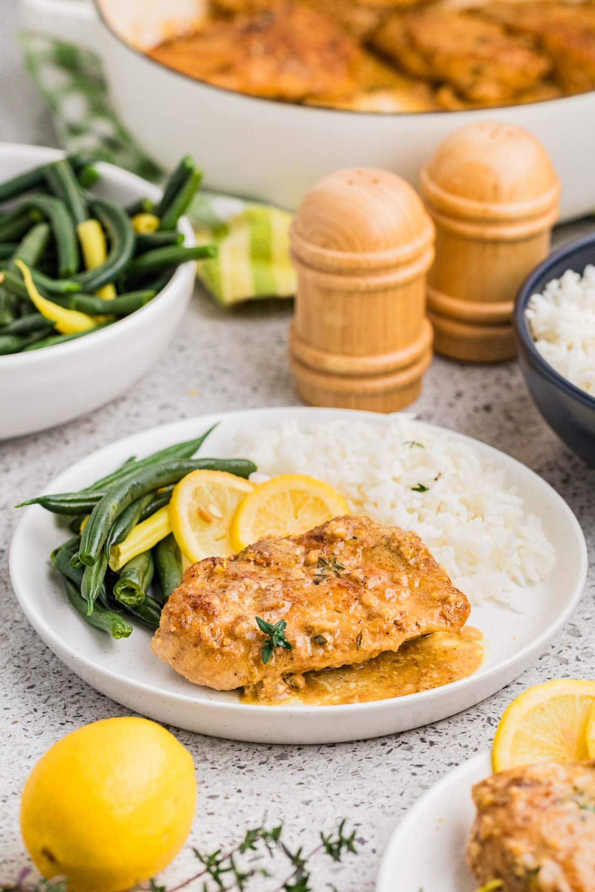 Lemon butter chicken served on a white plate with rice and green beans.