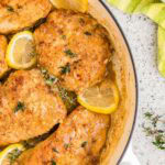 Close up shot of golden brown lemon butter chicken in a pan.