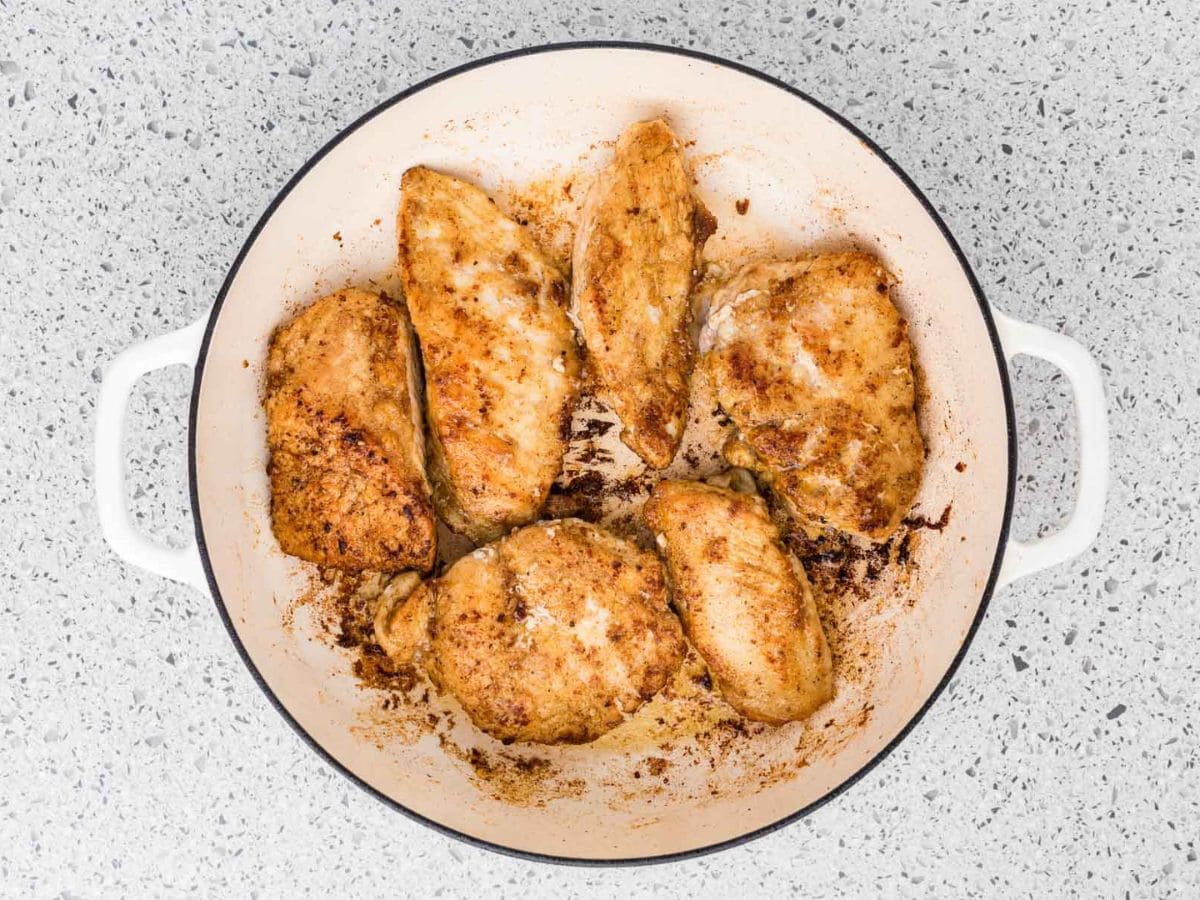 Chicken breasts in a pan after being seared on both sides.